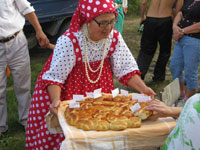 収穫祭にて、水玉の民族衣装で歓迎のパンをふるまう女性